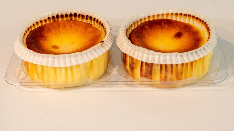 Two Trader Joe's Basque-style Cheesecakes unboxed, but still in plastic, on a white background