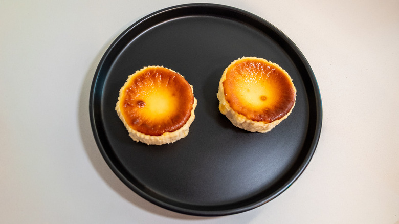 A top view of Trader Joe's Basque-style Cheesecakes on a black plate on a white background