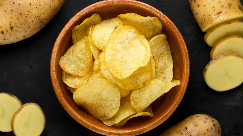 potato chips in a brown bowl against a black background