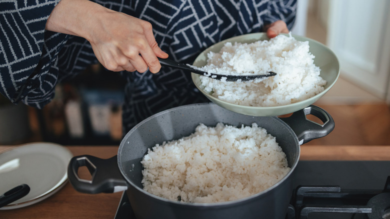 Person spooning rice from a pot to a plate