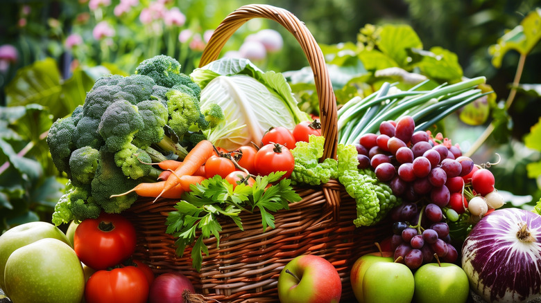 A basket full of fresh, seasonal fruit and veg, including carrots, tomatoes, apples, grapes, and broccoli