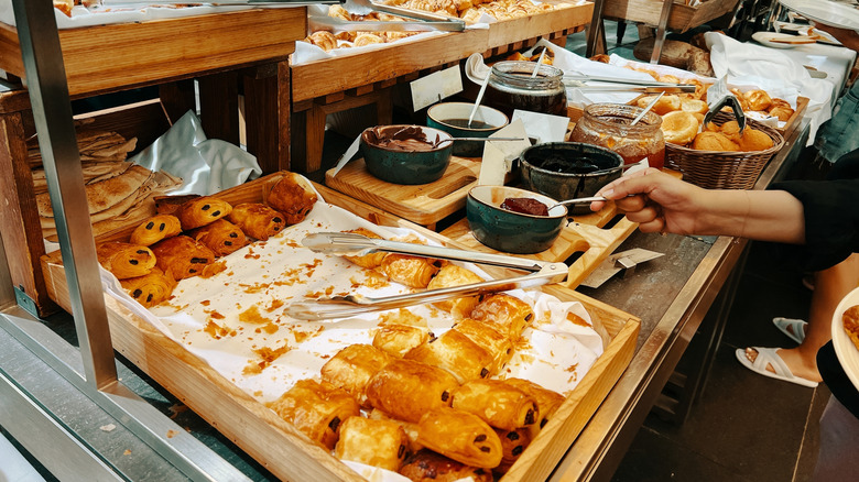 A hotel buffet breakfast with pastries, bread, and jam
