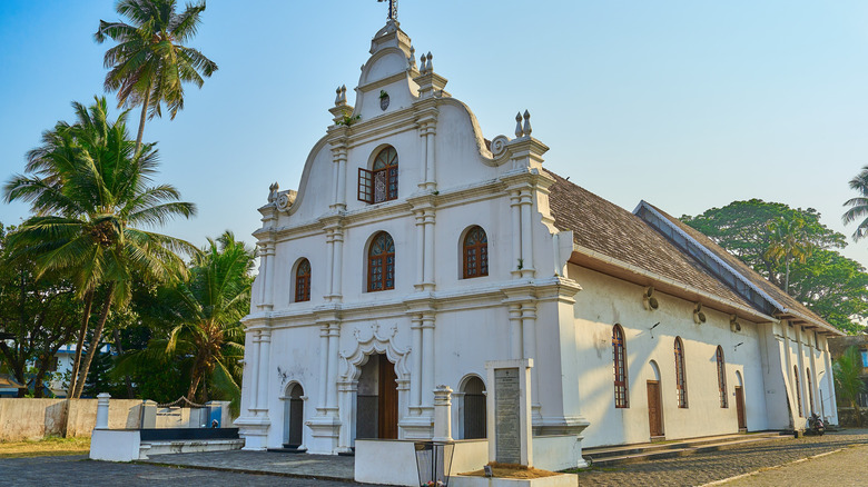 A church in a European city with palm trees in the background