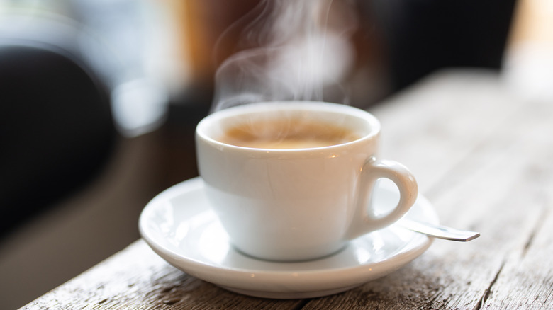 A steaming cup of espresso on a wooden bar