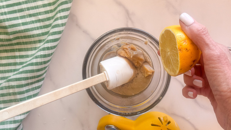 hand squeezing lemon into sauce