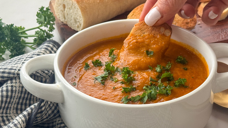 hand dipping bread into soup