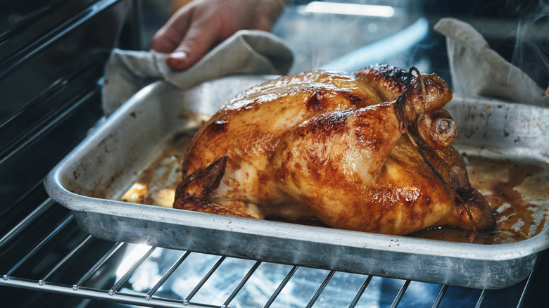 Chicken on baking tray being placed into an oven