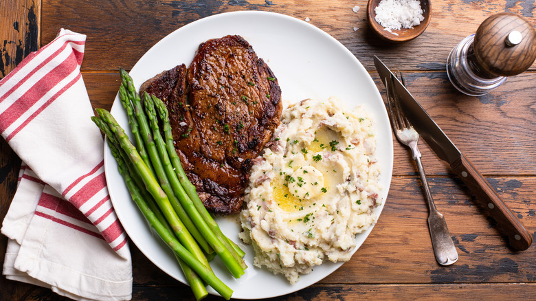 Steak dinner plate with mashed potatoes and asparagus