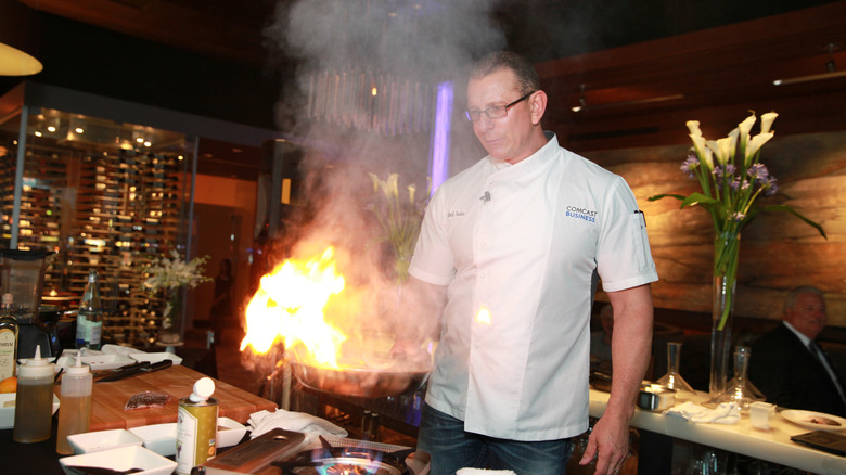 Robert Irvine cooking with fire in a pan