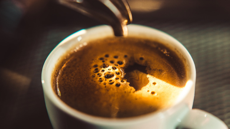 Espresso being poured into a white cup