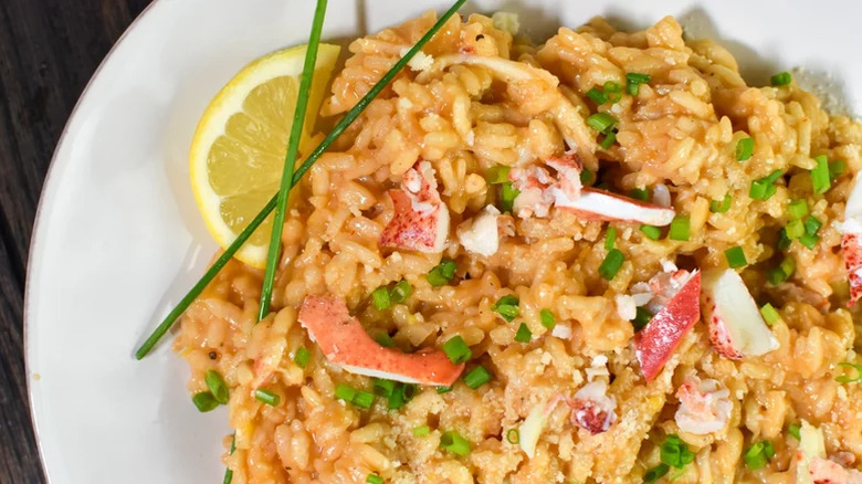 Lobster Risotto on a plate with herbs and lemon wedge.