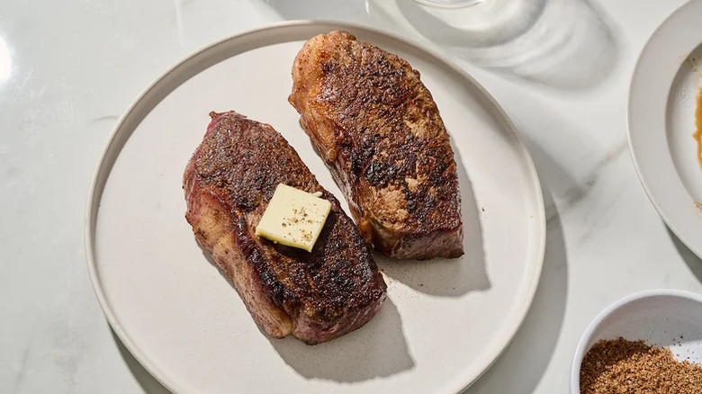 Bourbon steak on a plate topped with a pat of butter.