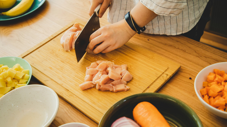 Cutting chicken on a wood cutting board