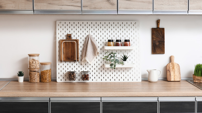 A spacious countertop with a peg board, complete with spices, a towel, and a cutting board
