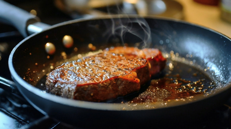 A steak searing in a frying pan