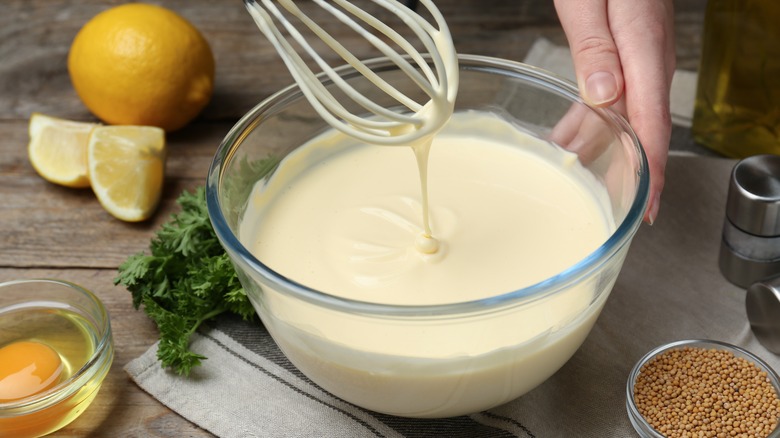 Person whisking fresh mayonnaise, glass bowl