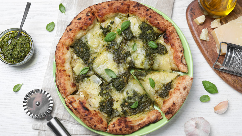 Pesto pizza with a bowl of pesto sauce on the side