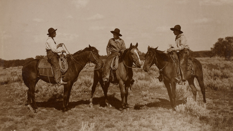 Sepia-tone photo of three cowboys on horseback