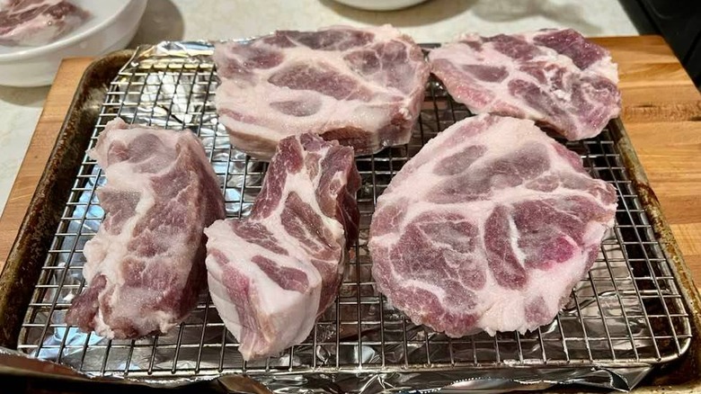 Salt pork on a cooling rack over a pan with aluminum foil