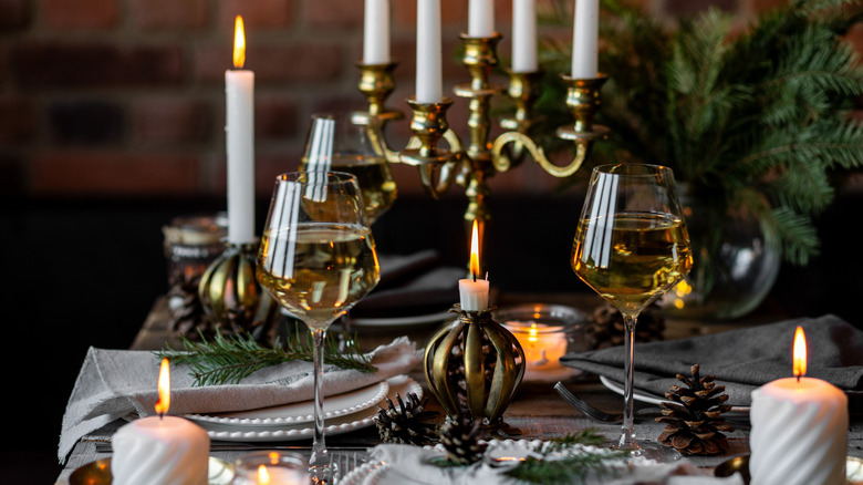 An elegant table setting for a dinner event complete with candelabra, candles with decorative holders, wine glasses, and plates