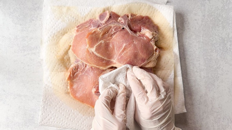 Patting brined pork chops dry with paper towels