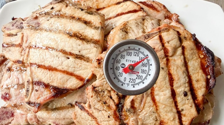 Instant read thermometer at 140 F inserted in grilled pork chops