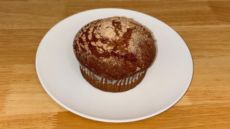 A cinnamon crunch muffin with a sugary top on a white plate.