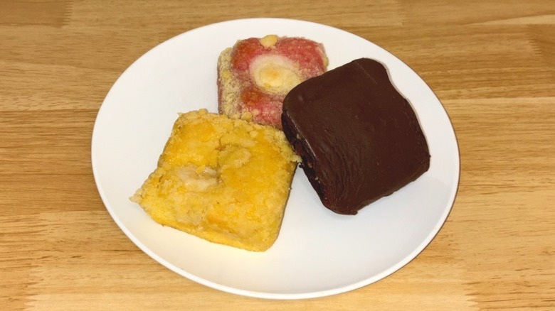 Lemon, chocolate, and strawberry loaf cakes on a white plate.