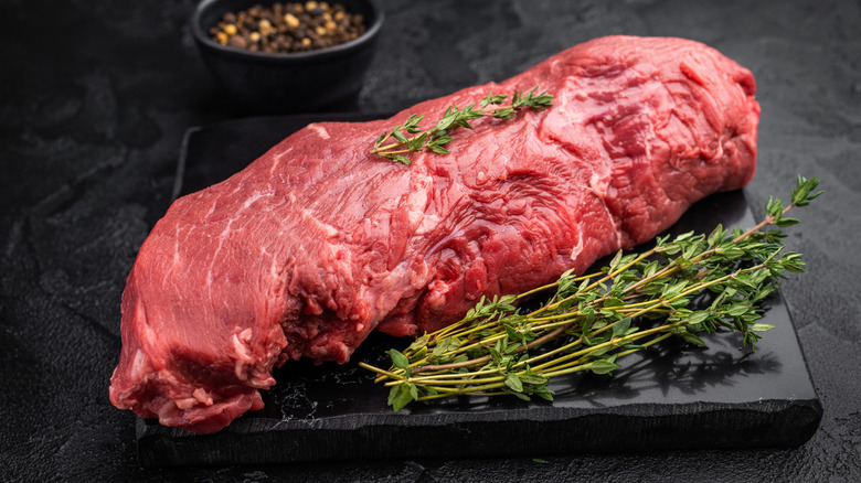 A whole raw tenderloin is styled with herbs and spices.