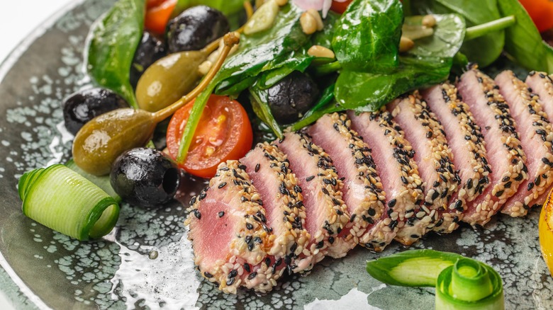 Sliced rare ahi tuna steak with olives and vegetables