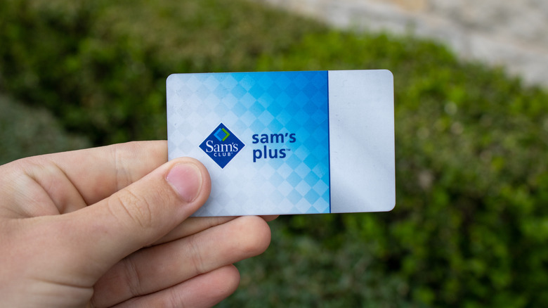 A hand holding a Sam's Club Plus member card