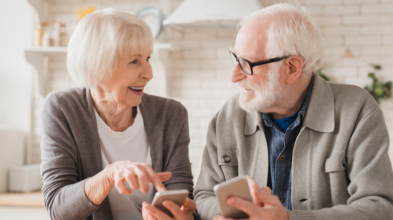 A senior couple talking and holding their cell phones.