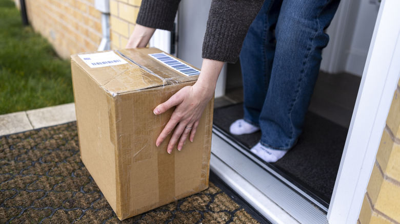 A woman picking up a package from her front porch