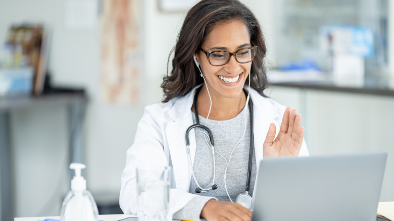 A doctor smiles at computer during a telehealth appointment
