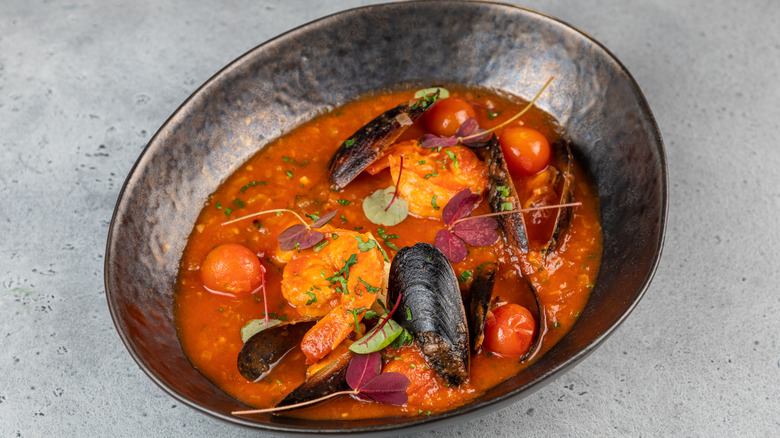 Traditional cioppino fish stew in ceramic bowl on counter top.