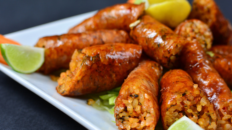 A platter of mombar rice sausage with lime wedges