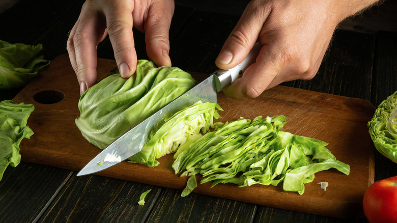 A pair of hands cutting cabbages with a knife