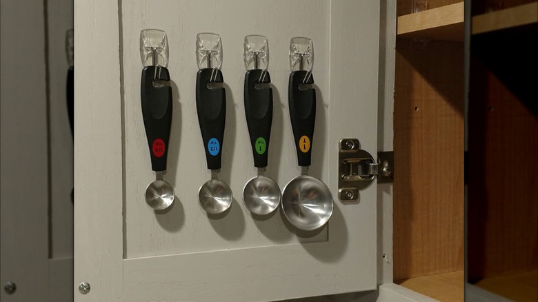 Measuring spoons hanging on adhesive hooks in cabinet