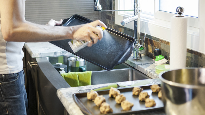 Person sraying cooking oil on baking tray