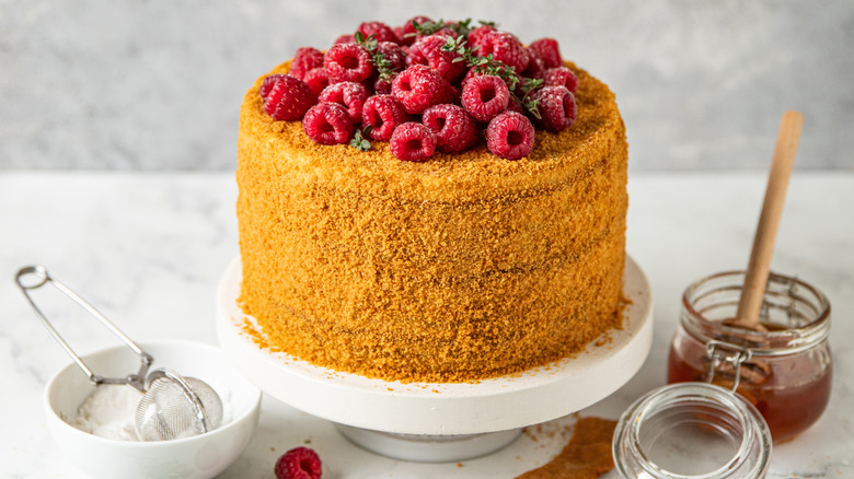 honey cake on a cake stand covered in berries