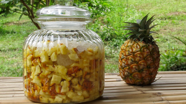 Pineapple vinegar in a glass jar with a whole pineapple on the side