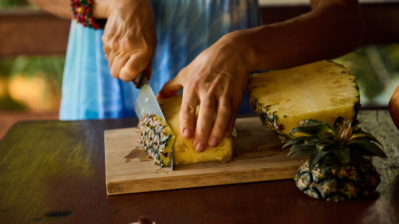 Person slicing a pineapple with a knife