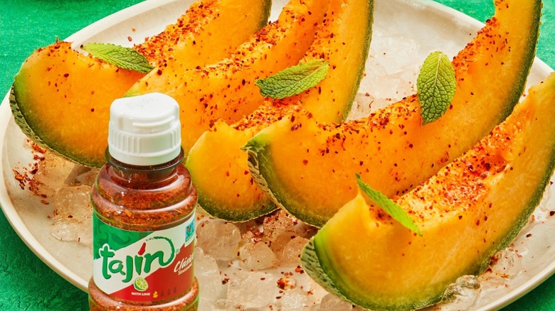 Slices of cantaloupe topped with Tajín seasoning and mint leaves