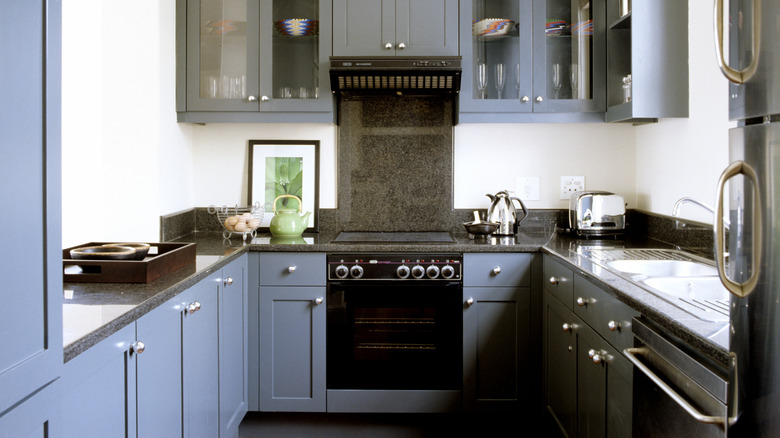 A kitchen with gray cabinets, with all eyes on the green artwork and teapot, showing that color can instantly add interest