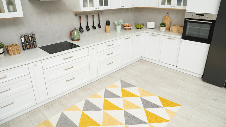 A white and gray kitchen with a colorful geometric rug