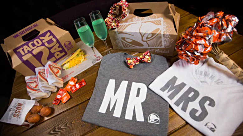 A spread showcasing a Taco Bell Taco 12 Pack, flutes of Mountain Dew Baja Blast, hot sauce bouquet and bow ties, and Mr and Mrs shirts