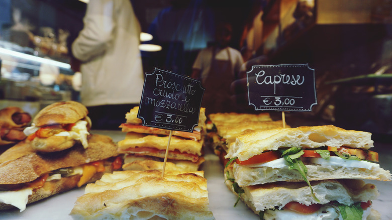 Italian sandwiches on display in a restaurant with kitchen staff in background