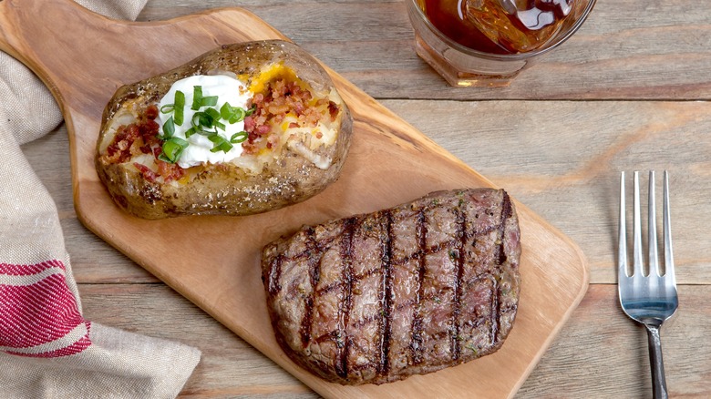 Glass of whisky with a steak on a wooden platter