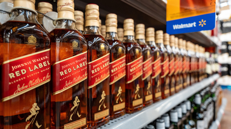 Bottles of Johnny Walker lined up on a store shelf.
