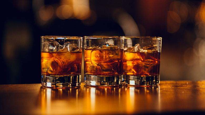 Whisky served with ice in three glasses.